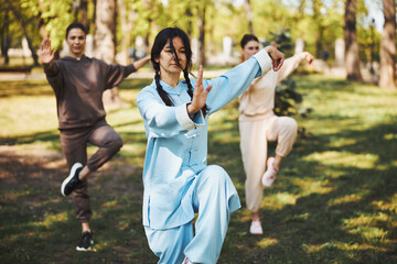 Tai chi trainer standing in crane pose before two students