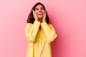 Young caucasian woman isolated on pink background laughs joyfully keeping hands on head. Happiness concept.