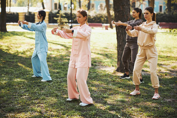 Qigong practitioners wrapping arms around empty space before them - obrazy, fototapety, plakaty