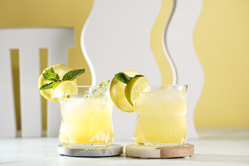 Two ice lemonade drinks in irregular glass with lime pieces and mint