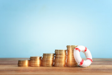 concept image of stacked coins and life bouy over wooden background. banking, funds and assistance...