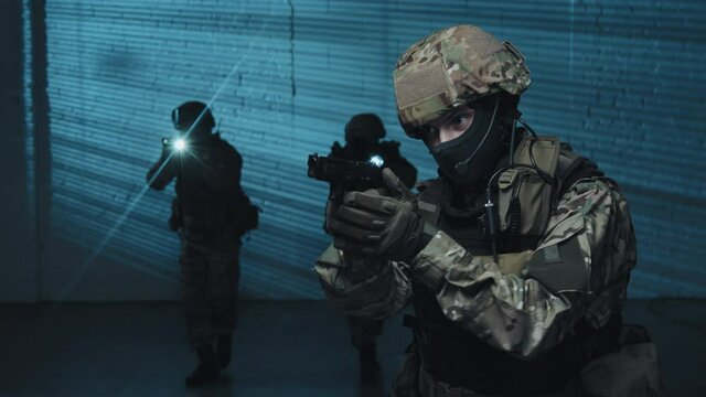 Medium shot with slowmo of special forces officer with gun doing gestures to signal something to other officers during raid