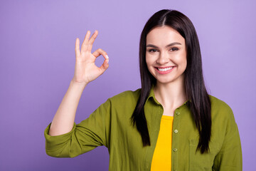 Photo of shiny adorable young woman wear khaki outfit smiling showing okey sign isolated violet color background