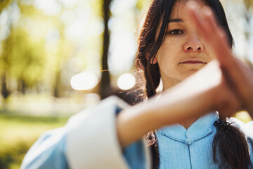 Female doing martial arts salute during tai chi lesson - obrazy, fototapety, plakaty