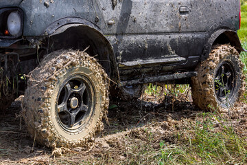 Fototapeta na wymiar black SUV with big wheels dirty in a swamp stands on the grass, the water flows from the body after being flooded in the river, close-up side view, nobody.