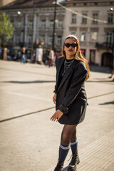 Obraz premium Beautiful country girl in 90s style. Back in time 90s 80s. Stylish girl in retro colourful vintage coat. dressed in street style clothes with chains around neck for a walk. Youth and lifestyle concept