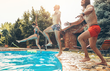 Friends jumping into the swimming pool.Having fun and refreshing on hot on summer day.	
