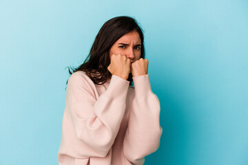 Young caucasian woman isolated on blue background throwing a punch, anger, fighting due to an argument, boxing.