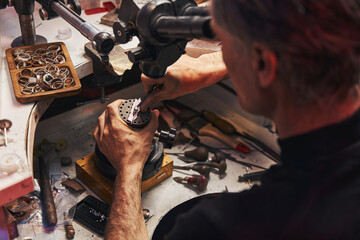 Jewelry maker using pusher tool during work on ring - obrazy, fototapety, plakaty