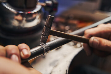 Craftsmen is peening silver ring with hammer