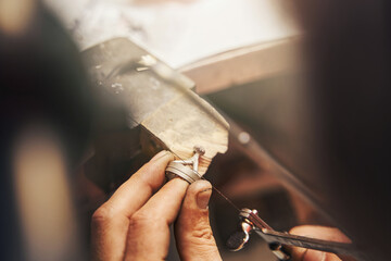 Goldsmith cutting metal piece with jeweler saw