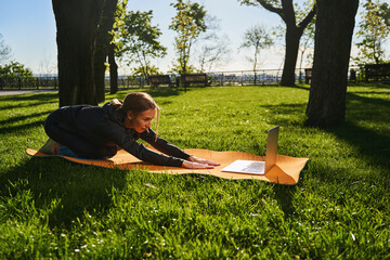 Cheerful female execising in park with notebook