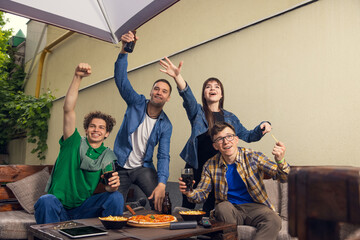 Sport fan club. Four young people, sportive fans meeting together in bar, pub. Concept of friendship, leisure activity, emotions and sport event