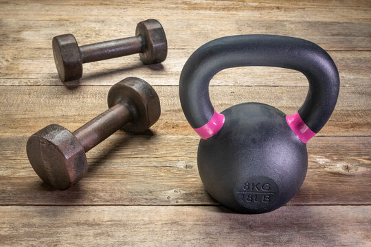 small iron kettlebell and a pair of dumbbells on a rustic wood background, exercise and fitness concept