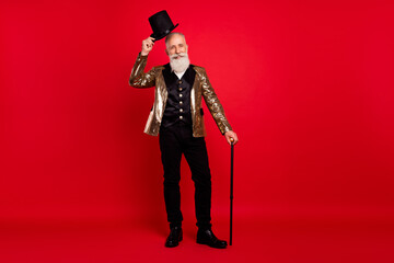 Full length photo of happy nice old man wear hat hold cane stick magician isolated on red color...