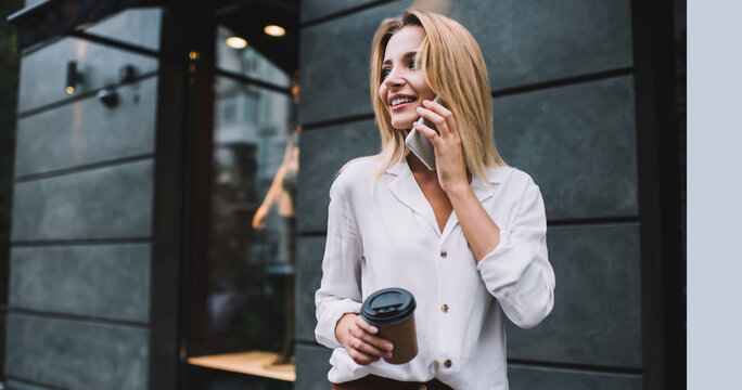 Smiling young female standing with coffee to go and calling