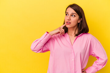 Young caucasian woman isolated on yellow background looking sideways with doubtful and skeptical expression.