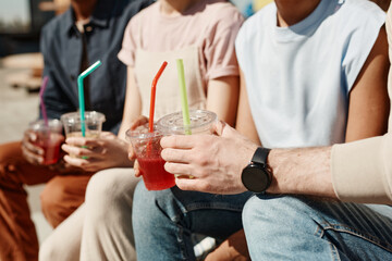 Close up of young people holding colordul cocktails while enjoying Summer in sunlight, copy space