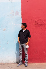 Obraz na płótnie Canvas Hispanic man standing in front of a colorful wall in the colonial city of antigua guatemala