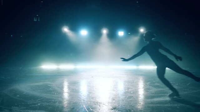 A girl skates and jumps at the ice rink in slow motion