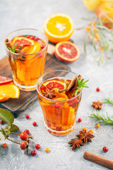 Winter or autumn hot healing tea with pear, orange, lingonberries, sea buckthorn and spices in glass cup.