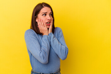 Young caucasian woman isolated on yellow background scared and afraid.