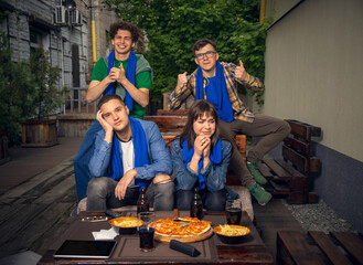 Four young people, sportive fans meeting together in bar, pub. Concept of friendship, leisure activity, emotions and sport event