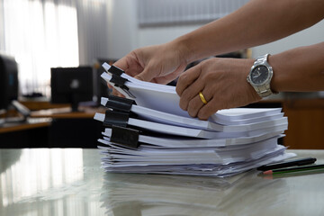 pile of unfinished papers on the desk a pile of business paper with the hands of a male employee searching for documents