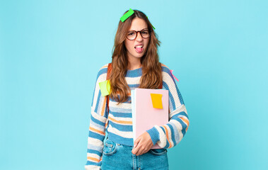 young pretty woman feeling disgusted and irritated and tongue out with a bag and holding books