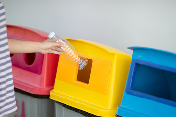 Woman throwing garbage into container. Recycling concept
