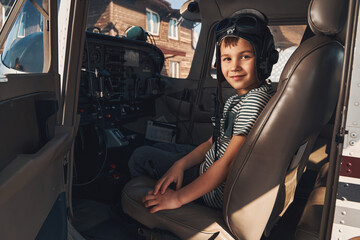 Adorable boy pilot sitting inside plane cockpit