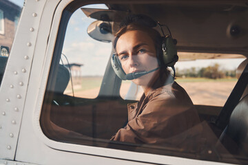 Attractive young woman sitting inside airplane cockpit