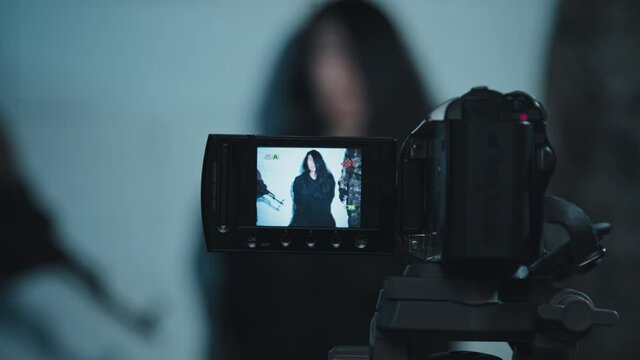 Handheld close up slowmo shot of video camera filming ransom message or confession of female hostage held by unrecognizable terrorists