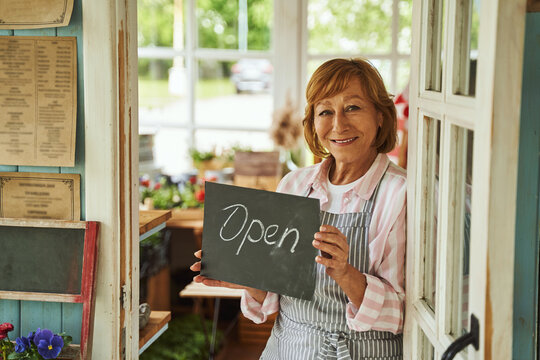 Happy woman welcoming customers to rural shop
