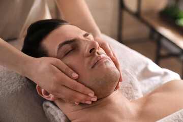 Fototapeta na wymiar Man receiving facial massage in beauty salon, closeup