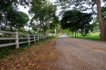 A white cement fence stretches along a gravel road.