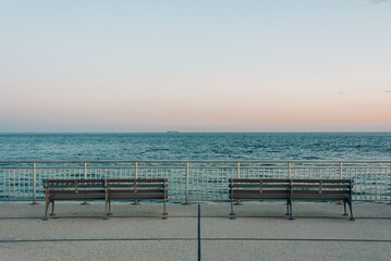 Fototapeta na wymiar Benches on the Rockaways Boardwalk and view of the beach, in Queens, New York City