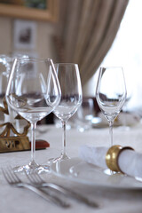 Festive table setting.Napkins made of cotton with brass rings. The concept of holidays.Wine glasses on the table. White plates. VIP lounge.White tablecloth with a textured pattern. Out of focus. 