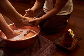 Pedicurist scrubing patient feet in spa cabinet