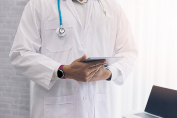 Doctor standing with stethoscope and holding tablet computer. Technology and medical concept.
