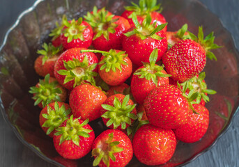 A small amount of ripe and juicy strawberries lies in a plate close-up