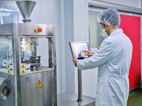 Man operating pharmaceutical machine at factory