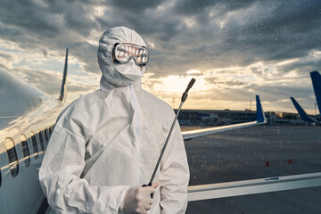 Worker in a hazmat suit spraying a disinfectant in the air