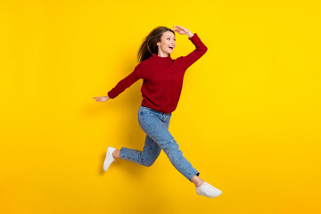 Fototapeta na wymiar Full length body size view of attractive amazed cheerful girl jumping walking searching news isolated over bright yellow color background