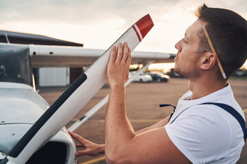 Male worker inspecting airplane propeller at aerodrome
