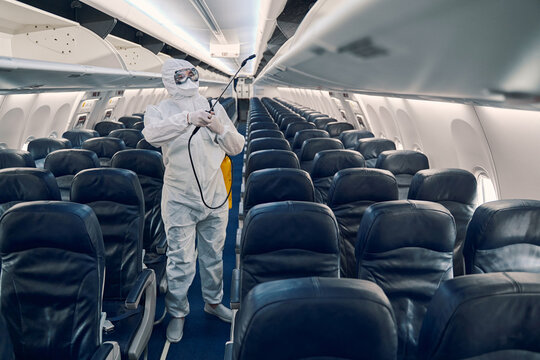 Man doing the antiviral disinfection aboard the plane