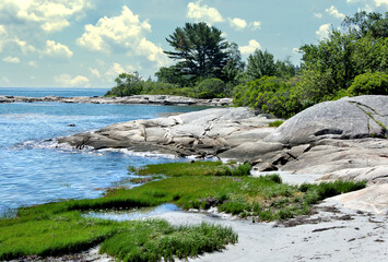 Tranquil summer scene in coastal Maine. View of small sand beach and huge granite boulders along...