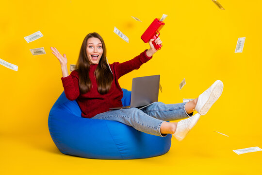 Full size profile side photo of young woman happy positive smile laptop fly air shoot money rich isolated over yellow color background