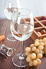 Glasses of white grape wine with grapes and wooden box on the background