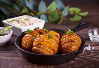 American traditional homemade Hasselback Potato with fresh herbs and bacon.